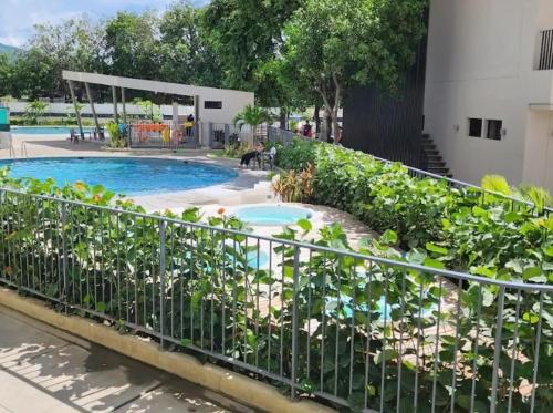 una valla con plantas junto a una piscina en Condominio, Bello Horizonte Plaza, Santa Marta., en Santa Marta