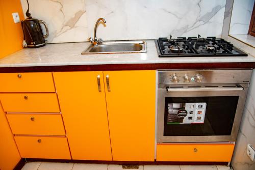 uma cozinha laranja com um lavatório e um fogão em EIREANN HOUSE Yassa em Douala