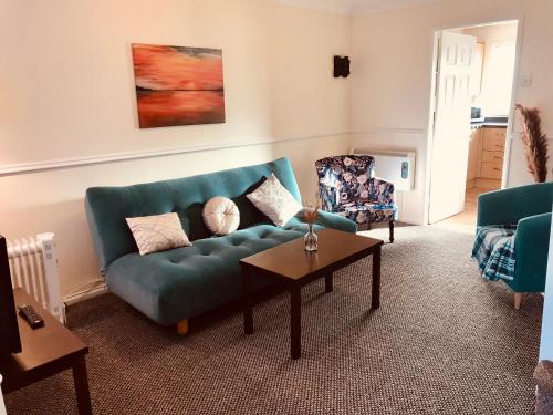 a living room with a blue couch and a table at Lavender Cottage in Thirsk