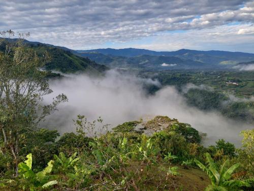 a view of a valley in the mountains with clouds at Cabaña Niraj in Cartago