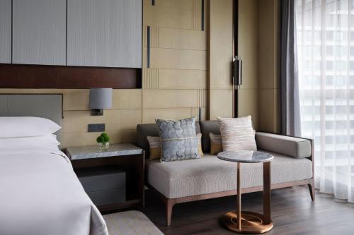 a bedroom with a bed and a couch and a table at Zhuhai Marriott Hotel Jinwan in Zhuhai