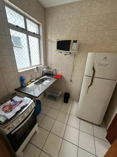 uma cozinha com um frigorífico branco e um lavatório em Pampulha 2 quartos completo em Belo Horizonte