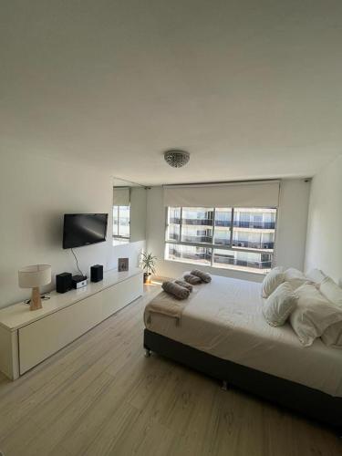 Habitación blanca con cama y TV en Apartamento en POCITOS vista al mar, en Montevideo