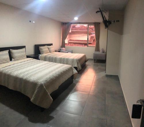 Habitación de hotel con 2 camas y ventana en Stelar Hostal, en Cuenca