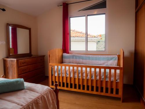 a crib in a bedroom with a window and a mirror at The House of Passos in Ponta do Sol