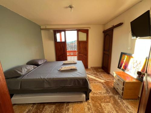 a bedroom with a bed and a television in it at HOSTAL LA CASA DE LOS SUEÑOS in Jardin
