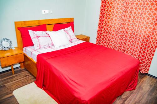 um quarto com uma cama vermelha e um cobertor vermelho em EIREANN HOUSE Yassa em Douala