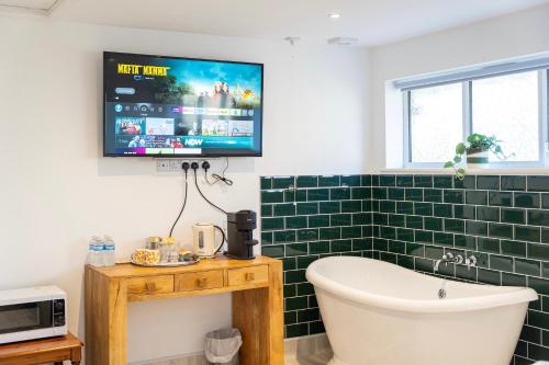 a bathroom with a tub and a tv on the wall at Soho House in Bordon in Bordon