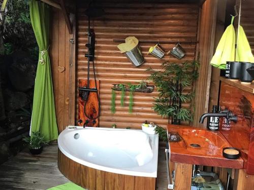 a bath tub in a bathroom with a wooden wall at Ma cabane in Deshaies