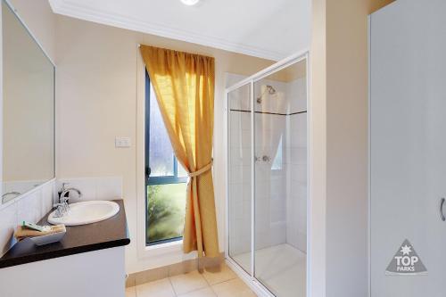 a white bathroom with a shower and a sink at Boomerang Way Tourist Park in Tocumwal