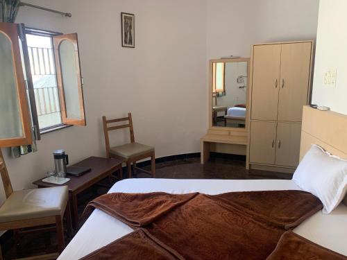 a bedroom with a bed and a desk and a mirror at Hotel Mount Way in Ābu Road