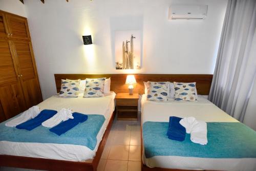 two beds in a hotel room with towels on them at El Pelicano Apart-Hotel in Las Galeras