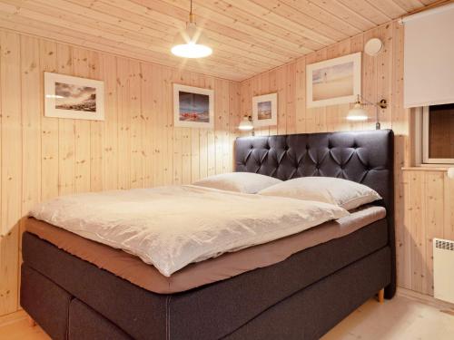 DannemareにあるHoliday home Dannemare XLIIIの木製の壁の客室の大型ベッド1台