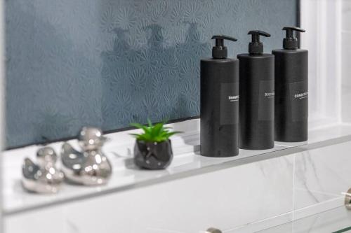 tres botellas negras sentadas en un estante en un baño en Convenient spacious house next Seven sisters station London en Londres