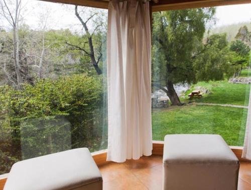 a living room with a large window and two chairs at Cabañas Rucaleufu in San Martín de los Andes