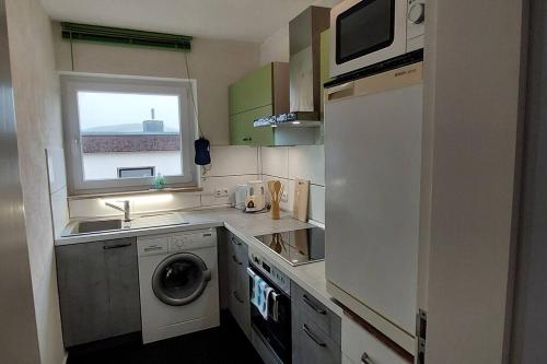 cocina pequeña con lavadora y ventana en Wohnung zum Wohlfühlen beruflich und privat, en Zell am Main