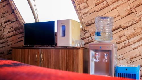 a bedroom with a tv and a dresser with glass bottles at Little Amanya Camp Amboseli in Amboseli