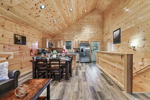 a log cabin kitchen with wooden walls and wooden tables and chairs at cul-de-sac Log Cabin, Hot-Tub, Arcade Games, In-Built Bunk beds, Level2 EV On site in Pigeon Forge