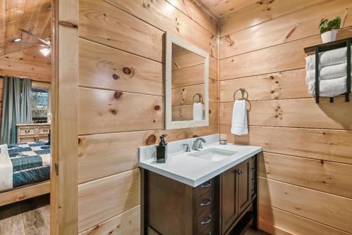 a bathroom with a sink and wooden walls at Mountains r Calling, Cozy Hideaway, King Beds, Hot-Tub, Arcade, EV Ready in Pigeon Forge