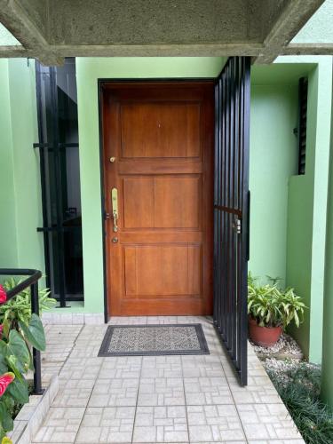 a wooden door on a green building with plants at The Rainier Bed & Breakfast 5 in San José