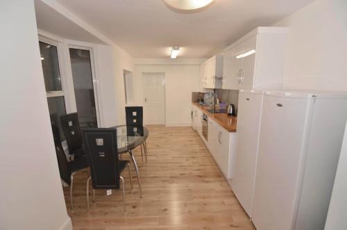 eine Küche mit einem Tisch und Stühlen sowie einem Kühlschrank in der Unterkunft Cosy Rooms near Canary Wharf & the O2 in London