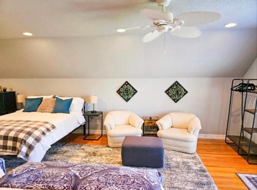 a bedroom with a bed and two chairs and a ceiling fan at Beaver Lake Hideaway in Lowell