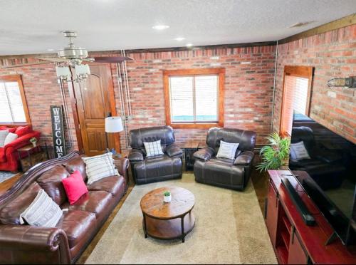 a living room with leather furniture and a brick wall at Beaver Lake Hideaway in Lowell