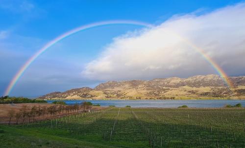 a rainbow over a field with a river and mountains at Glamping Dome - Pinot in Cromwell