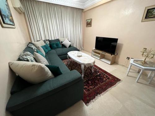 a living room with a green couch and a tv at Luxury apartment 3 in the heart of Gueliz, Wifi, Pool in Marrakech