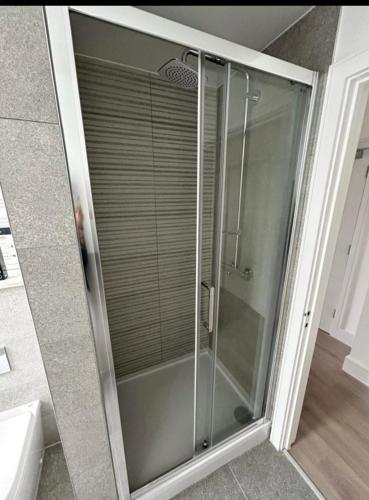 a glass shower in a bathroom next to a sink at The Penthouse Double Bedroom for Rent Use of kitchen in Epsom