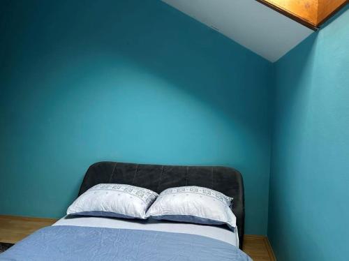 ein blaues Schlafzimmer mit einem Bett mit zwei Kissen in der Unterkunft Paradiso 5 in Bratunac