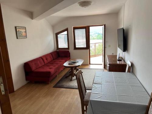 ein Wohnzimmer mit einem roten Sofa und einem Tisch in der Unterkunft Paradiso 5 in Bratunac