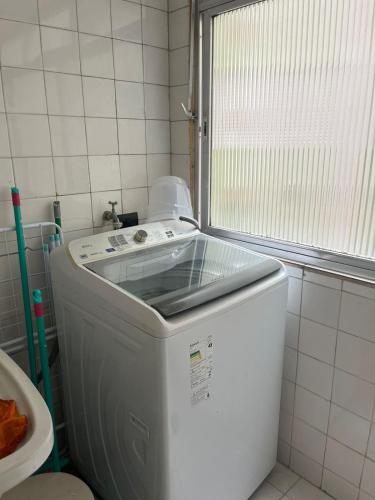 uma máquina de lavar roupa na casa de banho com uma janela em Apartamento Guaruja Enseada no Guarujá