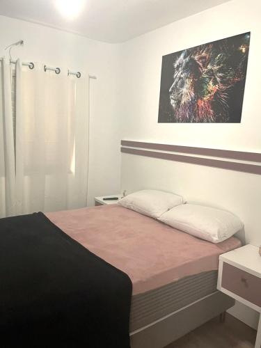 um quarto com uma cama e um quadro na parede em Apartamento Guaruja Enseada no Guarujá