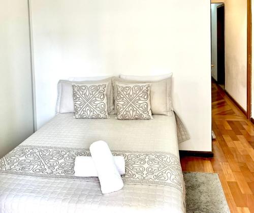 1 dormitorio con 1 cama con sábanas y almohadas blancas en Pérola do Aquarius, en São José dos Campos