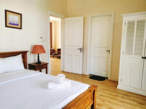 a bedroom with a bed and two white doors at Bougainviella - Sealinks Mũi Né - chuỗi biệt thự liền kề in Phan Thiet