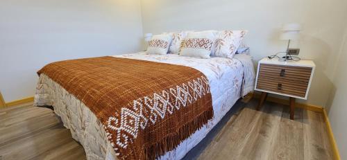 a bedroom with a bed and a night stand at Cabañas Pewmawapi in Quellón