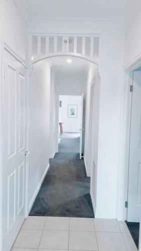 un pasillo con paredes blancas y una puerta blanca en Foxy's Cottage, en Point Cook