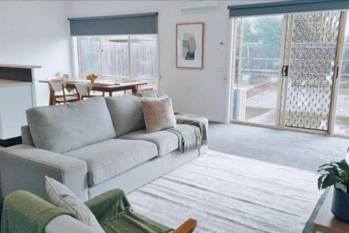 sala de estar con sofá y mesa en Foxy's Cottage, en Point Cook