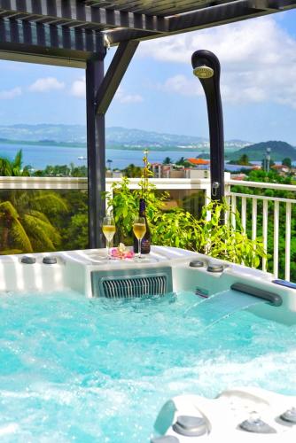 a hot tub with two glasses of wine in it at Villa Sweet Caraïbes, vue mer, jacuzzi in Les Trois-Îlets