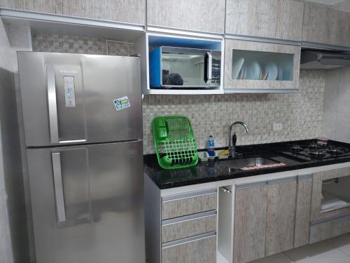 a kitchen with a stainless steel refrigerator and a sink at Cantinho de vó - Praia Grande - Aviação in Solemar