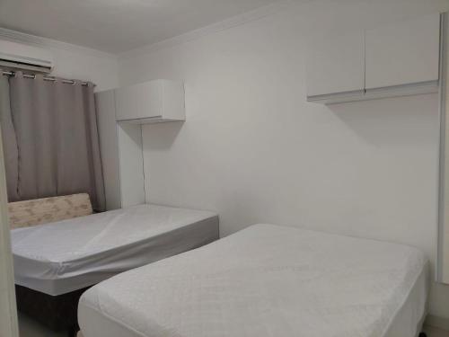 Solemar的住宿－Cantinho de vó - Praia Grande - Aviação，配有白色墙壁的小客房内的两张床