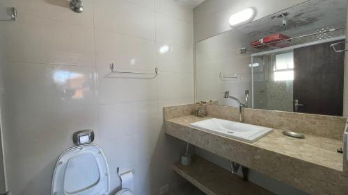 ein Badezimmer mit einem Waschbecken, einem WC und einem Spiegel in der Unterkunft Edificio Daniela Ap 102 in Bombinhas