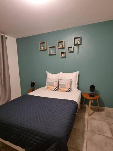 a bedroom with a bed with a blue wall at T3 ZAC HIBISCUS in Cayenne