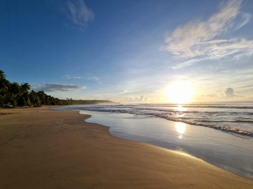 a beach with the sun shining on the water at Relax Beach House in Tangalle
