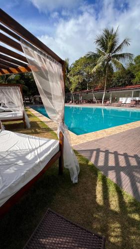 a bed with a canopy next to a swimming pool at Verde Mar Pipa Beach in Pipa