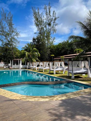 a swimming pool with two white chairs around it at Verde Mar Pipa Beach in Pipa