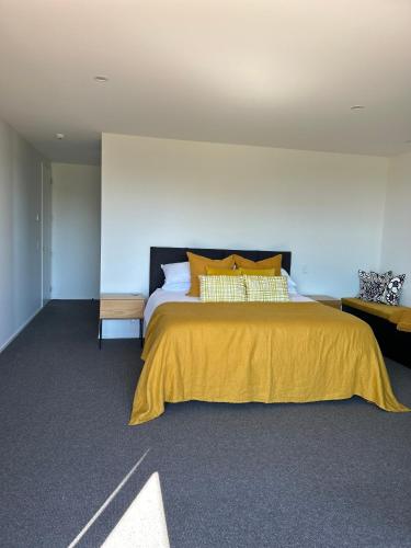 a bedroom with a large bed with a yellow bedspread at Harakeke Boutique Accommodation in Mahana