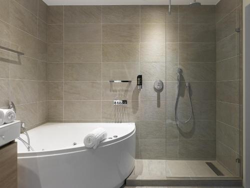 ein Bad mit einer Dusche, einer Badewanne und einem WC in der Unterkunft Romantik Parkhotel het Gulpdal in Slenaken