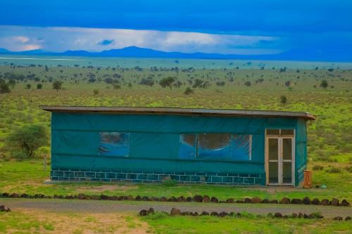 a blue building in the middle of a field at Amanya 1-Bed Zebra Tent in Amboseli